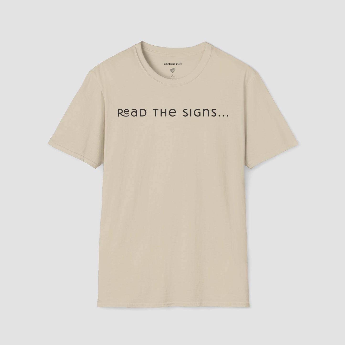 Beige t-shirt with 'READ THE SIGNS...' text on a light gray background