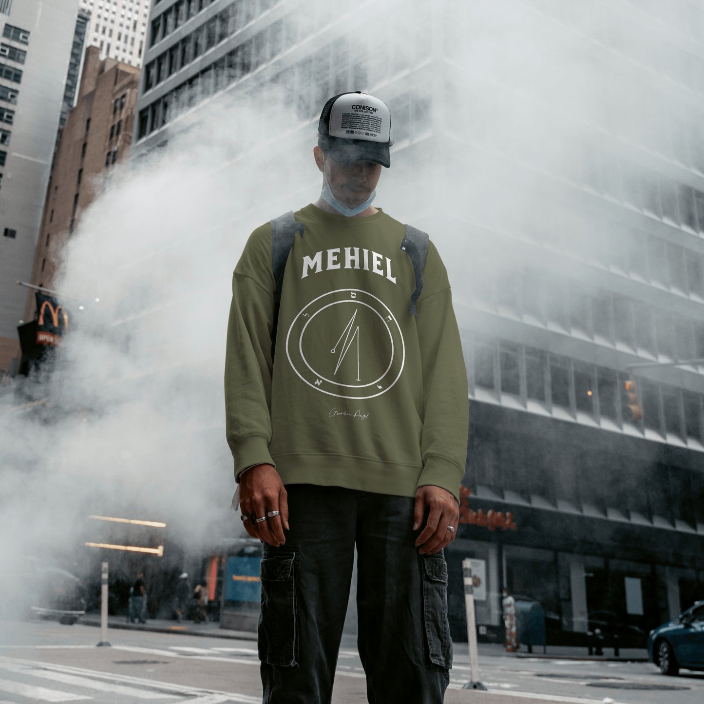 Model wearing a No.64 Shemhamphorasch Guardian Angel "Mehiel" Sweatshirt in Military Green. With the seal of Mehiel in white print on the front.