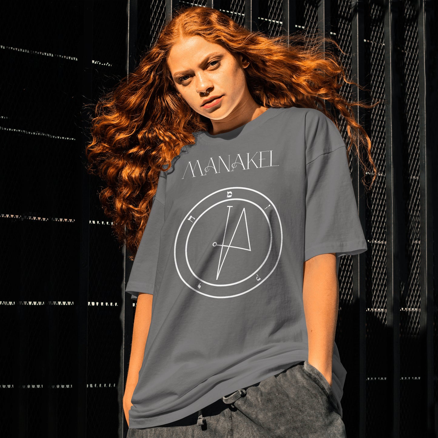 Model wearing No.66 Manakel Shem Hamephorash Guardian Angel T-Shirt in charcoal with symbol of Manakel on front.