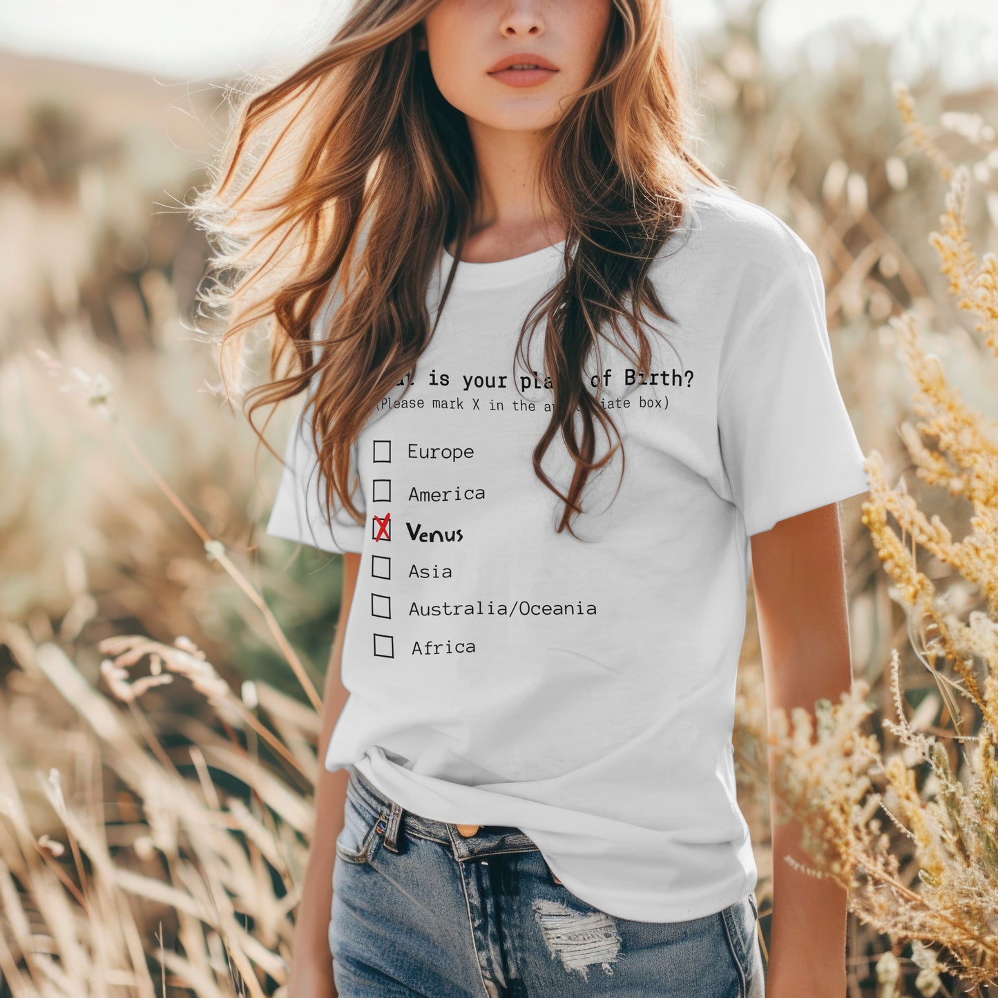 Model wearing white T-shirt featuring a humorous checklist design that asks 'What is your place of birth?' with options like Europe, America, and Venus, where Venus is marked with a red X.