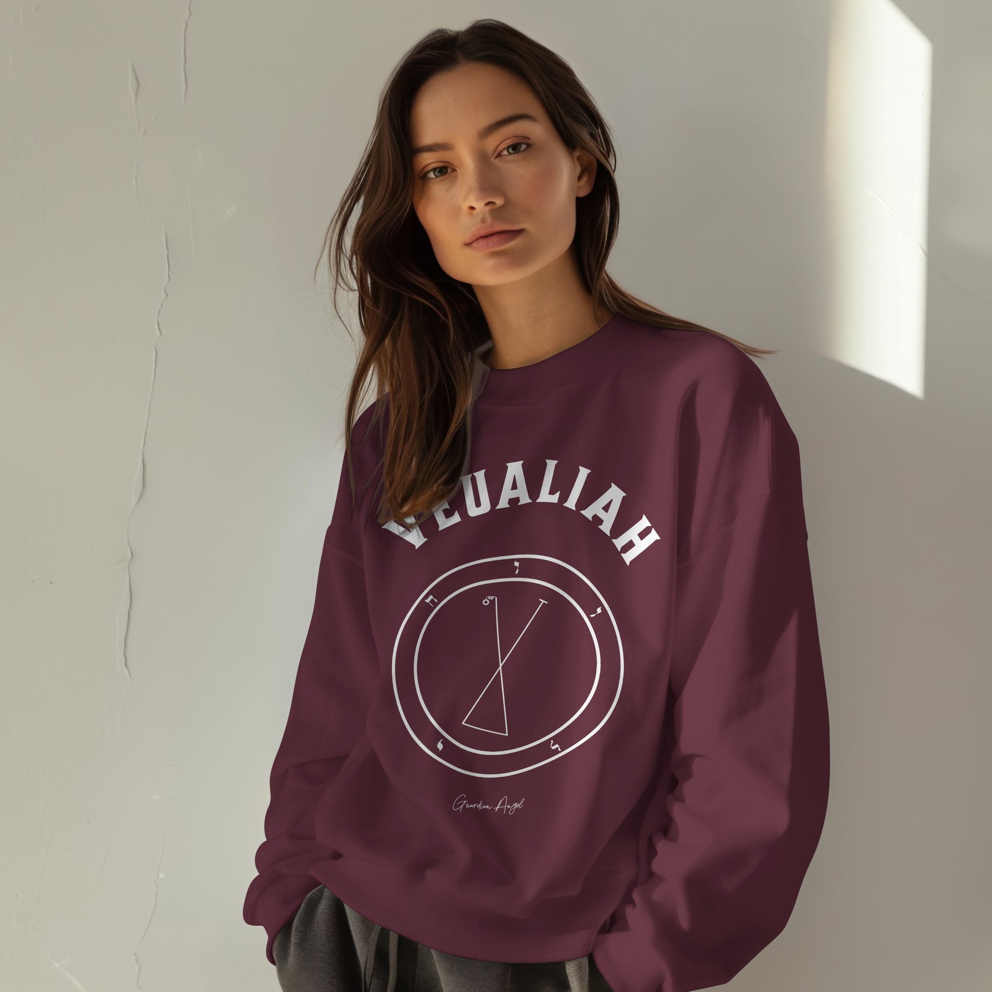 Model wearing a No.43 Shemhamphorasch Guardian Angel "Veualiah"  Sweatshirt  in Maroon. With the seal of Veualiah in white print on the front.