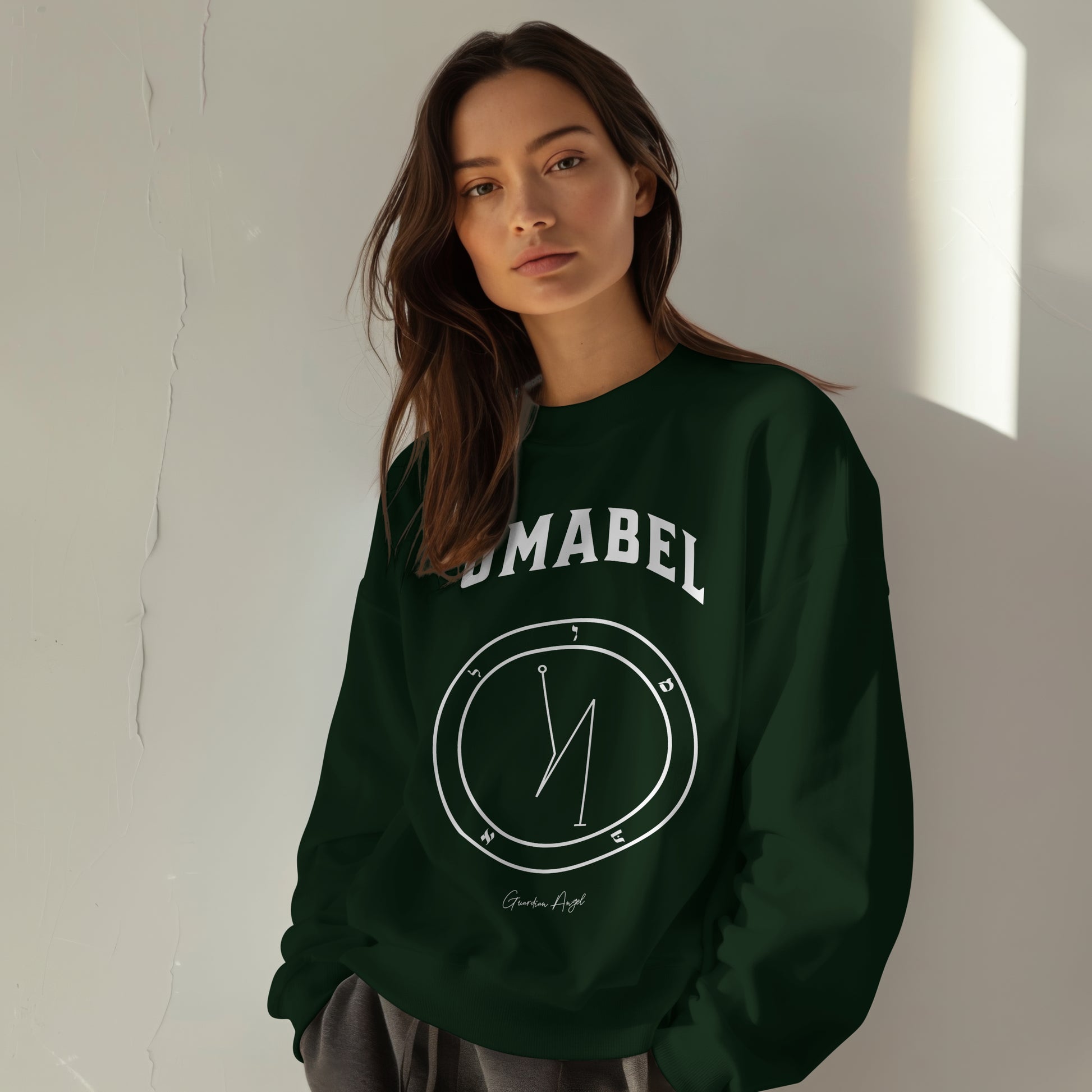 Model wearing a No.61  Shemhamphorasch Guardian Angel "Umabel"  Sweatshirt  in Forest Green With the seal of Umabel in white print on the front.