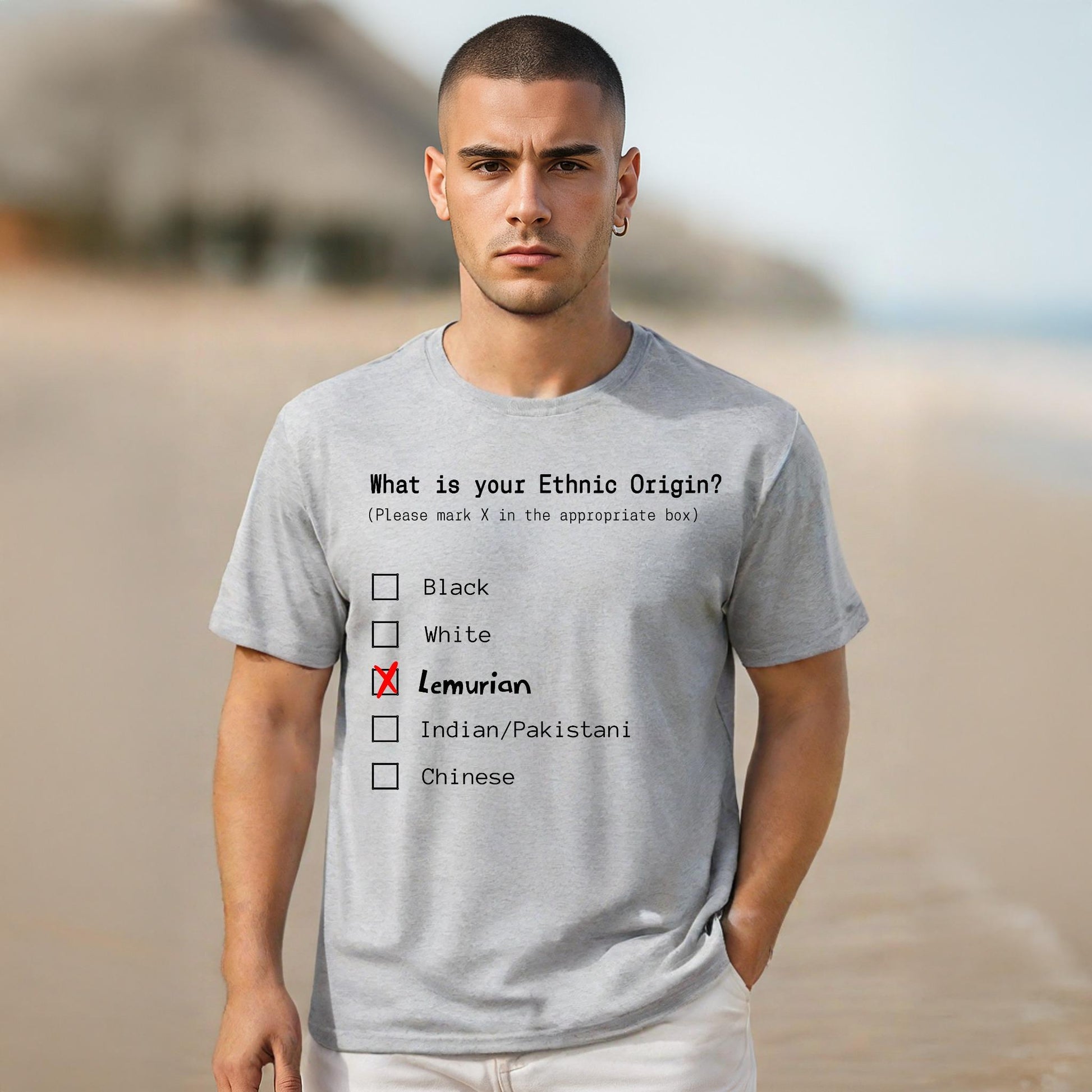 Man wearing a gray t-shirt with a humorous ethnic origin quiz on a beach.